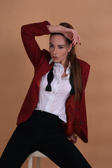 Portrait of a fashionista in the studio dressed in an elegant jacket and trousers, barefoot