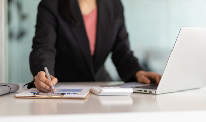 Obraz premium Businesswoman finance market analyst working on laptop pointing at business finance report chart document on desk in office. Finance and bookkeeping concepts using computer software.