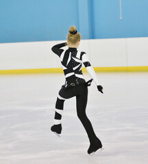 Girl figure skating rolls on a skating rink with artificial ice