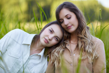 Fototapeta premium Two young women brunette and blonde are standing in a field.