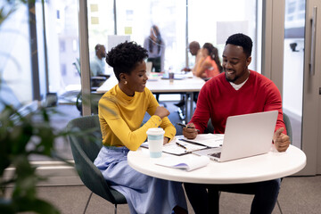 Smiling african american male and female advisors planning strategy together with laptop at office