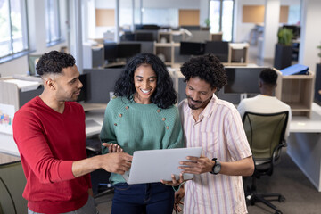 Happy multiracial young advisors discussing together over laptop at modern workplace