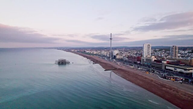 Aerial view of calm sea, empty beach with Brighton i360 and quiet seafront at dawn in UK