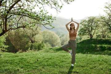 A woman walks in the park and does yoga and enjoys the fresh summer air. Lifestyle and mind and body health care