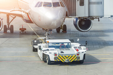 Towing truck pushing back ready to tow the plane jet to the parking place at the airport.