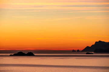 Fototapeta premium Panoramic sunset view from Praiano at Mediterranean Sea, Italy, Campania, Europe. Silhouette of Li Galli islands and coastline of Amalfi Coast. Reflection of sun beams on water surface during twilight