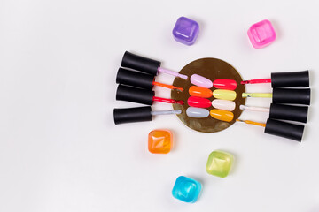 brushes from bottles of gel polish lie on a white background along with tips of the same colors. palette of gel polish shades together with brushes
