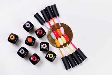 a collection of multi-colored gel lacquers on a white background. black bottles and brushes with...