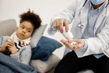Obraz na płótnie Canvas Cropped photo of male pediatrician give a medicines for sick little black girl