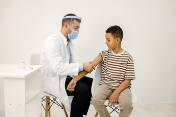 Male doctor doing a vaccination to a multiracional boy