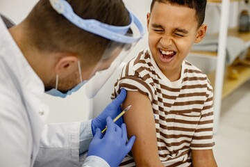 Male doctor doing a vaccination to a multiracional boy