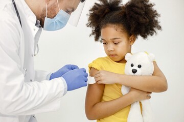 Male doctor stick a band-aid on a girl's shoulder after a vaccination