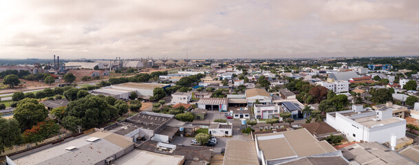 Drone aerial view of Sorriso city skyline, buildings, houses and BR 163 road on cloudy summer day, Amazon, Mato Grosso, Brazil. Concept of cityscape, landmark, architecture, logistics, transport. - obrazy, fototapety, plakaty