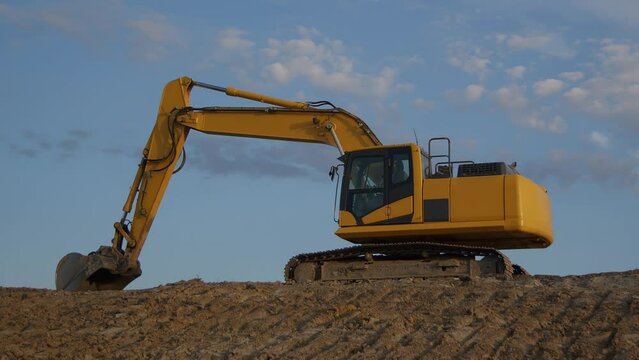 construction site excavator heavy shovel yellow hydraulic equipment dirt digger earth mover time lapse blue sky and clouds