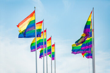 Obraz premium Rainbow flag fluttering against blue sky, Pride LGBT community symbol