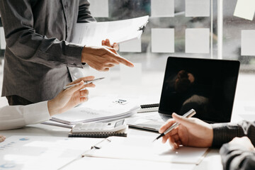 A desk in a company conference room has a group of business people attending and with supporting documents laid out, brainstorming sessions to fix and plan the company's growth. Business meeting idea.