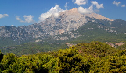 Naklejka premium Panoramic view of Tahtalı mountain, which is slightly obscured by clouds, with dense forest in the foreground near the town of Kemer, Antalya region, Turkey 