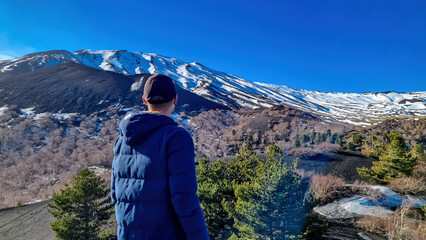 Tourist man hiking on volcanic landscape of volcano mount Etna, in Sicily, Italy, Europe. Pine and...