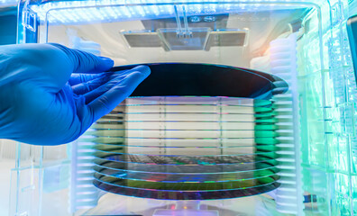 Gloved Hand Holding a Silicon Wafer in plastic holder box used in electronics for the fabrication...
