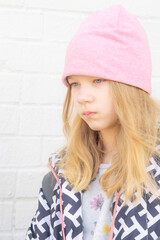 vertical portrait of an upset girl against a white wall