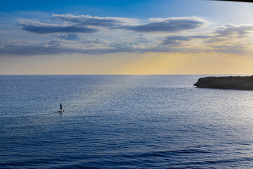 Paddle surf (Stand up surf) a la puesta de sol en la playa de Binigaus de Menorca (Islas Baleares, España)