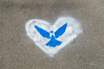 blue pigeon in a white heart on the asphalt