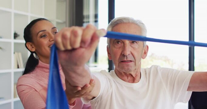 Video of happy biracial female physiotherapist exercising with caucasian senior man