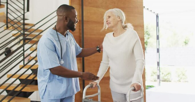 Video of happy african american male doctor taking care of caucasian senior woman