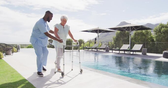 Video of happy african american male doctor taking care of caucasian senior woman in garden