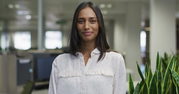 Video of happy biracial woman looking at camera in office
