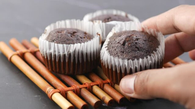 close up of hand pick chocolate muffin on table 