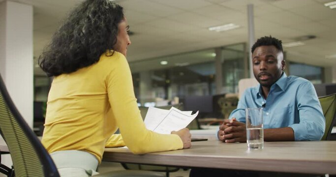 Video of happy diverse businessman and businesswoman talking about project and shaking hands