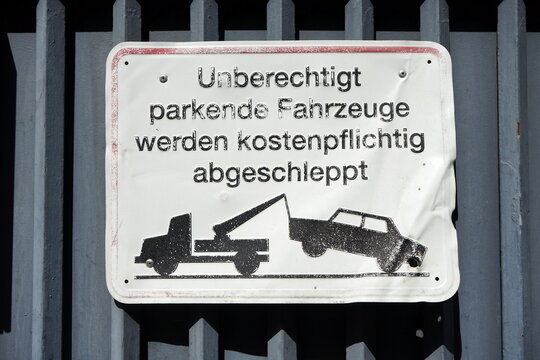 Zerbeultes Blechschild mit Abschleppwagen an einer Hofeinfahrt mit grauem Stahltor bei Sonnenschein in der Berger Stra&szlig;e im Stadtteil Bornheim in Frankfurt am Main in Hessen