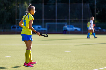 Young field hockey female player with stick during the game. Image with copy space
