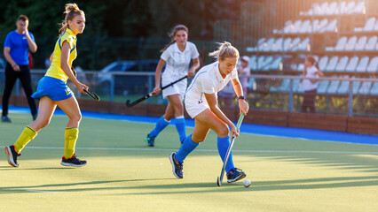 Young girl lead the ball in attack during field hockey game.