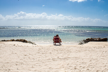 Fototapeta na wymiar man sitting on a beach chair on a bright day on the beach
