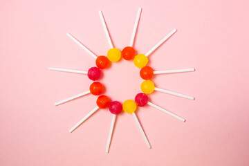 Lollipops are laid out in the shape of a circle on a pink background. Various fruit candies. sweet treat