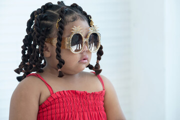 African hairstylist braided hair of afro little girl, wears fashion sunglasses