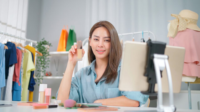 Young Asia woman workin online e-commerce shopping at home. Startup online fashion cloth business. Set up live streaming by using tablet video call show product to customer. Buy and sell concept