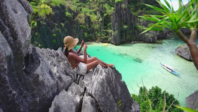 Woman Sitting On Limestone Rocks Taking Photo With Smartphone