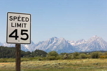 Verkehrsschild in Amerika mit Tempolimit fünfundvierzig.
Verkehrszeichen in Front einer Gebirgskette aus dem National Park Great Teton in den USA.