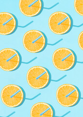 Summer trendy pattern made of round orange slices with straws on bright blue background. Minimal citrus fruits concept.  Creative vacation idea. Flat lay.