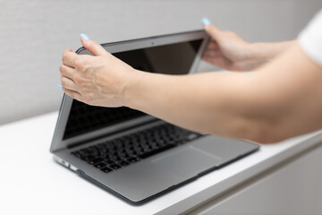 woman closes laptop lid with her hands