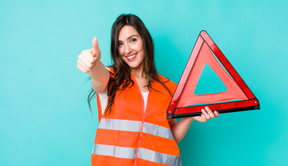 young pretty woman  feeling proud,smiling positively with thumbs up. car emergency triangle