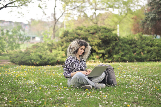 young woman uses a computer in a park