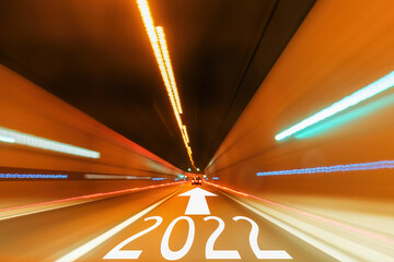 2022 text and forward arrow written on the road in the tunnel with blurred light. New Year plans...