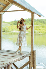 Young woman standing on the wooden pier at the calm lake