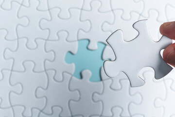 Hand holding piece of jigsaw puzzle. Flat lay, Directly above.