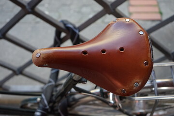 Brauner klassischer Fahrradsattel aus Leder eines alten Fahrrad an einem Rautengitter in der Berger...
