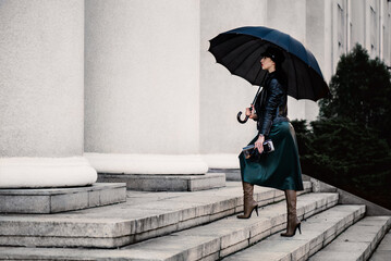 Young woman under an umbrella walking the stairs.